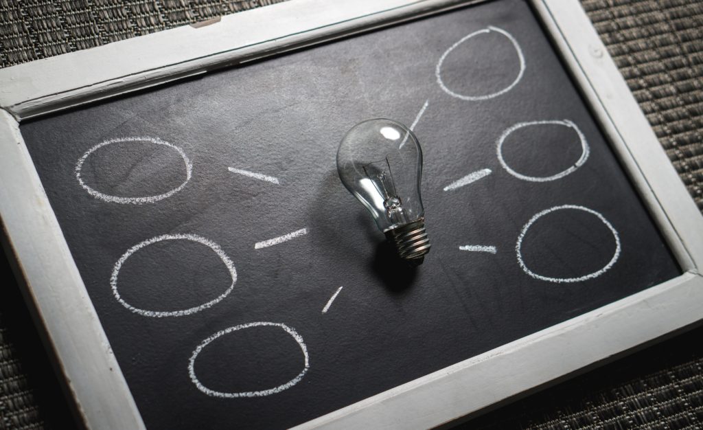 Board with light bulb in the middle and icicles branching off, representing business ideas. 